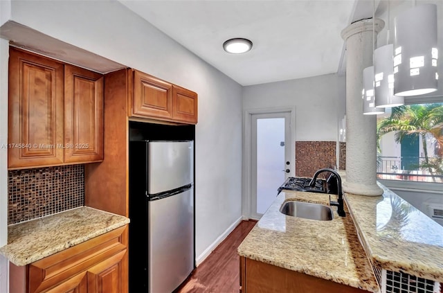 kitchen with light stone counters, sink, backsplash, and stainless steel fridge