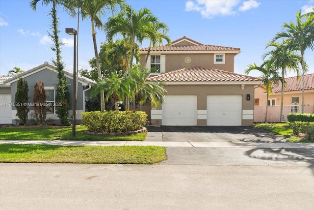 mediterranean / spanish-style home featuring a garage, driveway, a tiled roof, and stucco siding