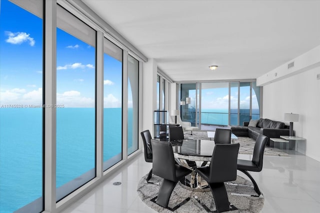 tiled dining area featuring a water view and a wall of windows