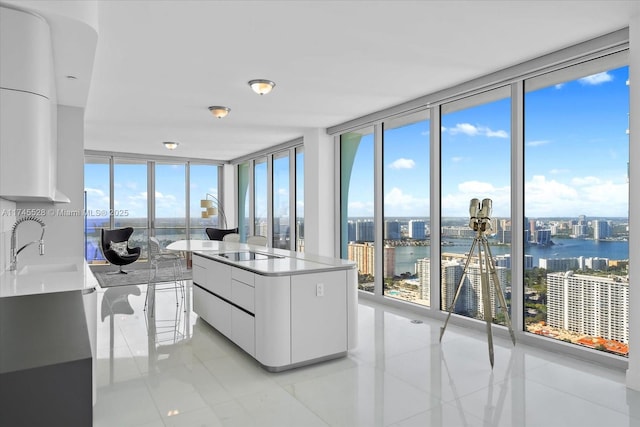 kitchen featuring a water view, a center island, white cabinets, and a wall of windows