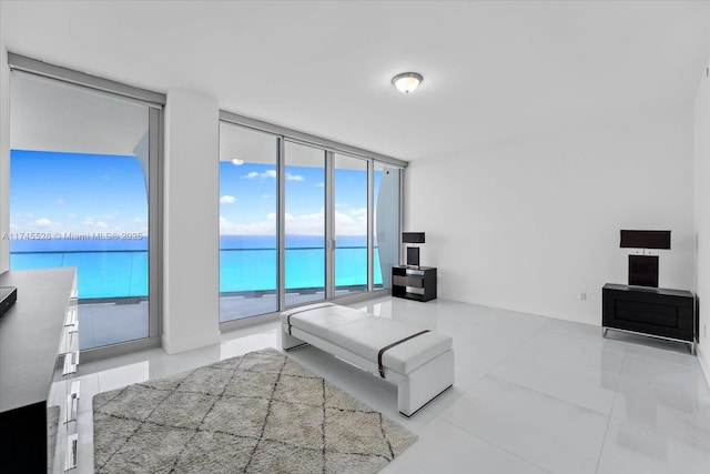 bedroom with floor to ceiling windows, a water view, and access to outside