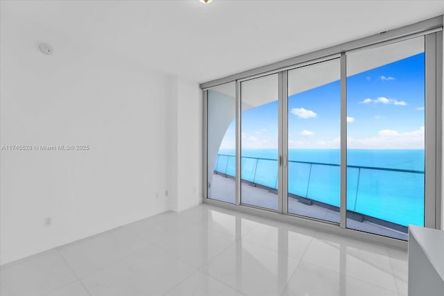 empty room with light tile patterned flooring and a water view