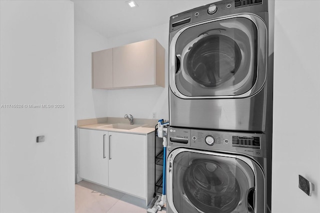 washroom with stacked washer / drying machine, sink, cabinets, and light tile patterned flooring