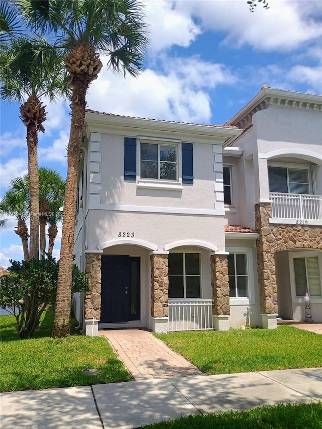 view of front of house featuring a front yard, stucco siding, and stone siding