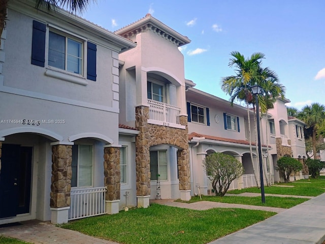 view of front of property with stucco siding, stone siding, and a front lawn