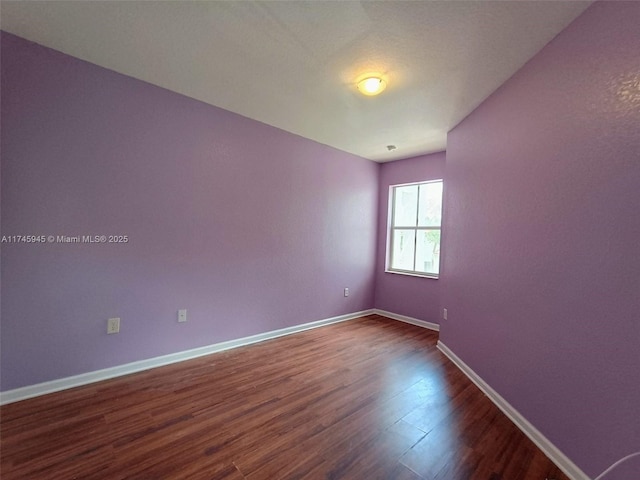 empty room featuring dark wood-type flooring and baseboards