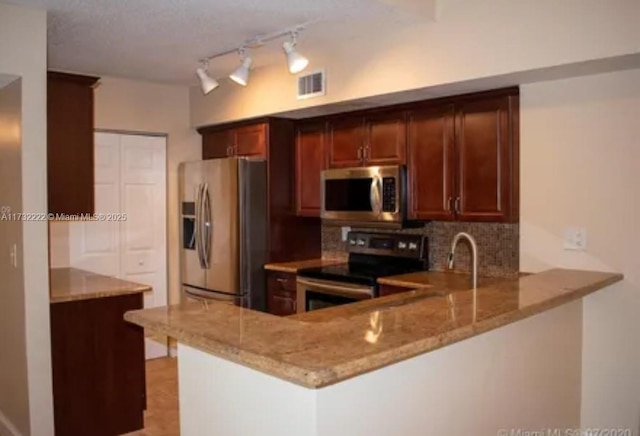 kitchen featuring tasteful backsplash, stainless steel appliances, kitchen peninsula, and light stone counters