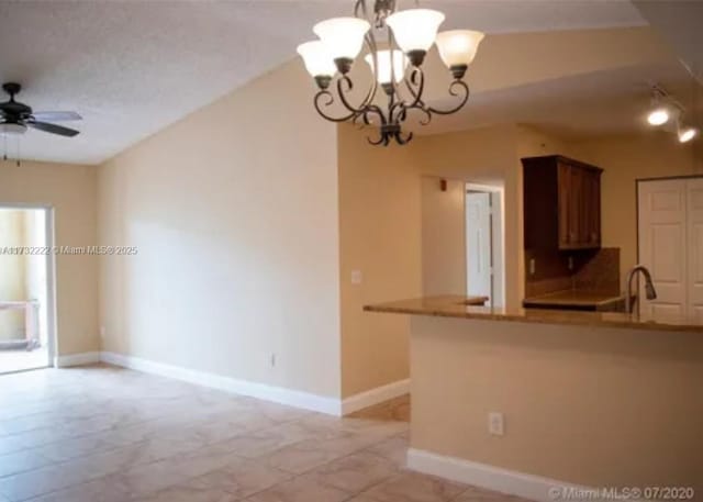 kitchen featuring ceiling fan with notable chandelier, pendant lighting, lofted ceiling, kitchen peninsula, and a textured ceiling