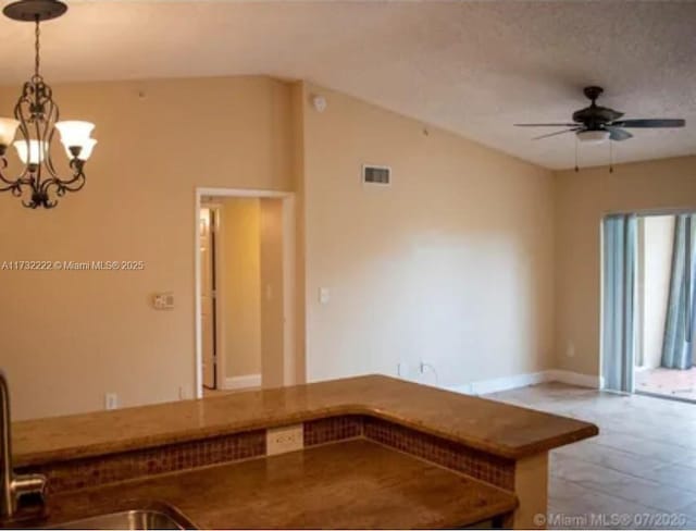 kitchen featuring ceiling fan with notable chandelier, sink, pendant lighting, and a textured ceiling