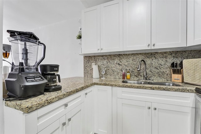 kitchen with sink, backsplash, white cabinets, and light stone counters