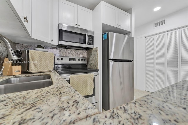 kitchen featuring light stone counters, stainless steel appliances, sink, and white cabinets