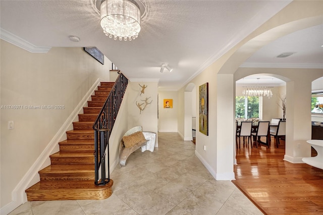 entrance foyer with arched walkways, stairs, visible vents, and an inviting chandelier