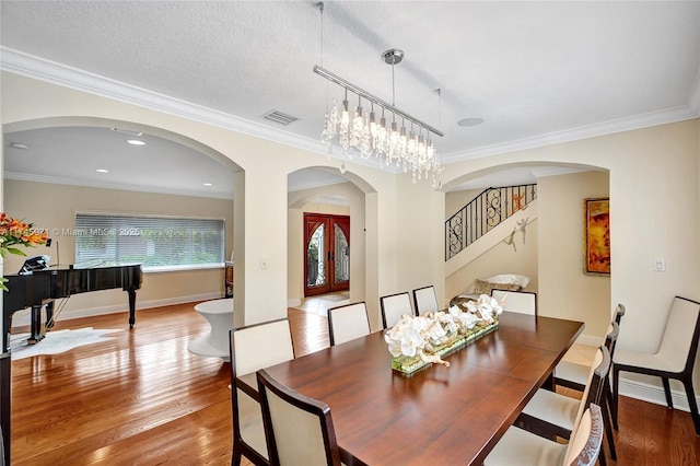 dining space featuring light wood-style floors, baseboards, visible vents, and ornamental molding