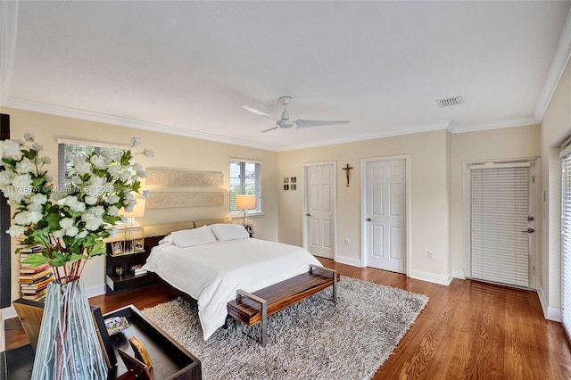 bedroom featuring ornamental molding, dark wood finished floors, visible vents, and baseboards