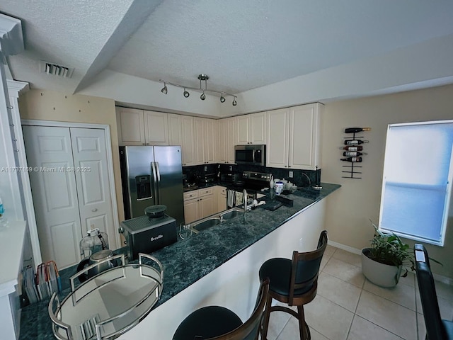 kitchen with light tile patterned flooring, sink, kitchen peninsula, stainless steel appliances, and backsplash