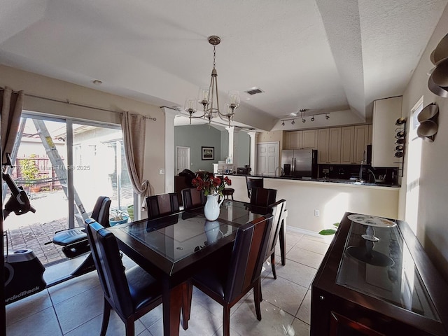 dining room with decorative columns, lofted ceiling, a chandelier, light tile patterned floors, and a textured ceiling