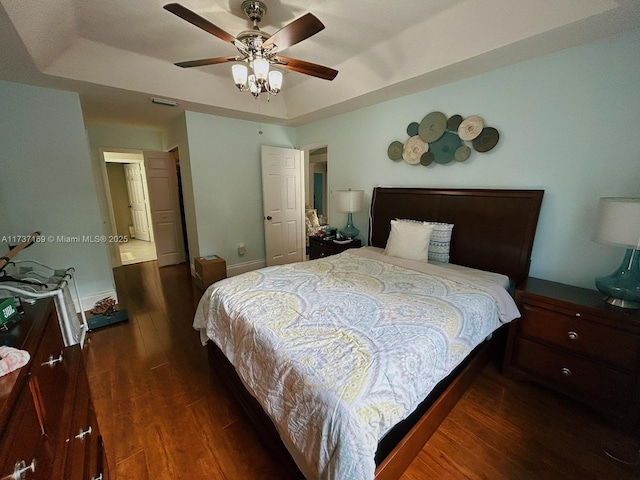 bedroom featuring dark hardwood / wood-style flooring, a tray ceiling, and ceiling fan
