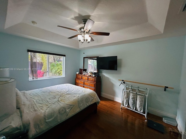 bedroom featuring dark hardwood / wood-style floors, ceiling fan, and a tray ceiling