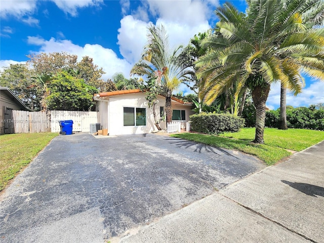 view of front facade featuring driveway, fence, a front lawn, and stucco siding