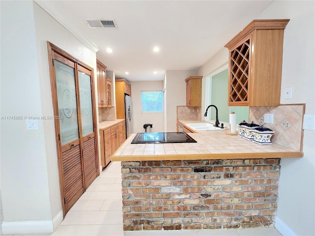 kitchen with visible vents, tile counters, a sink, and freestanding refrigerator