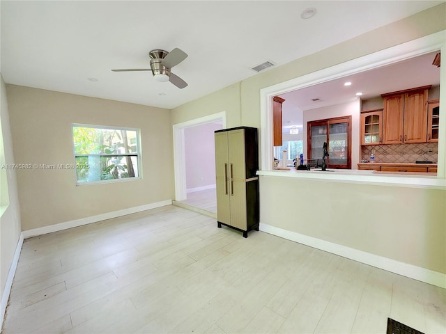 unfurnished room with light wood finished floors, baseboards, visible vents, and a ceiling fan