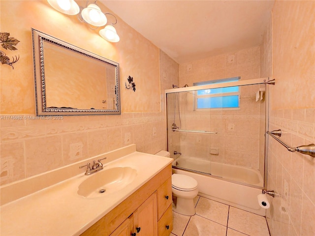 full bathroom with toilet, tile patterned floors, combined bath / shower with glass door, vanity, and tile walls