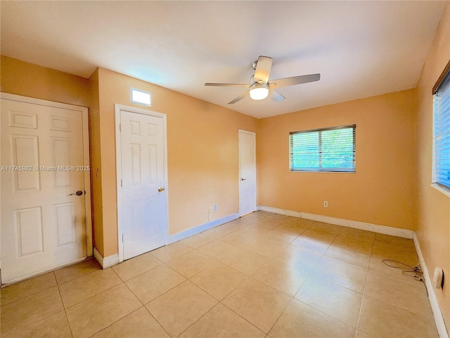 unfurnished bedroom with light tile patterned floors, a ceiling fan, and baseboards