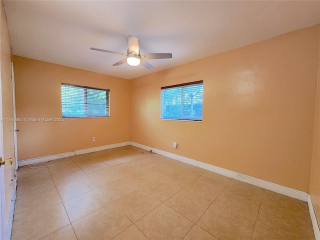 empty room with a ceiling fan, a healthy amount of sunlight, and baseboards