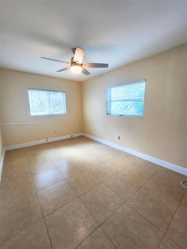 tiled empty room featuring a ceiling fan, a wealth of natural light, and baseboards