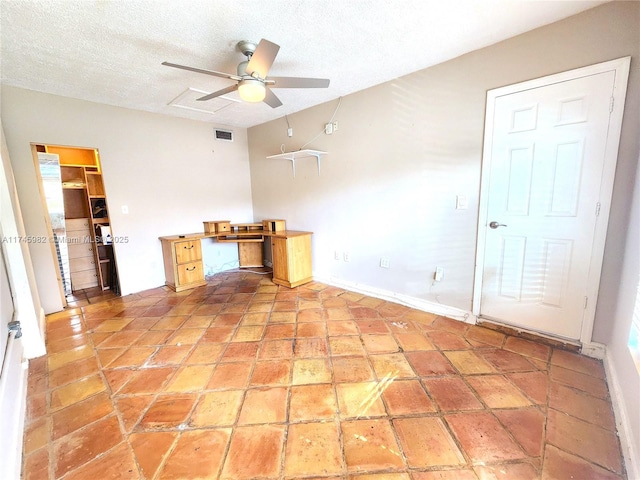 unfurnished office with baseboards, ceiling fan, visible vents, and a textured ceiling