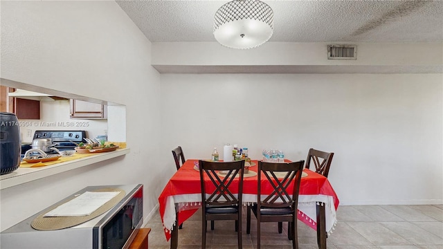 dining space featuring a textured ceiling and light tile patterned floors