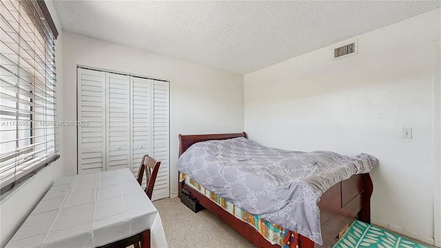 bedroom featuring carpet, a closet, and a textured ceiling