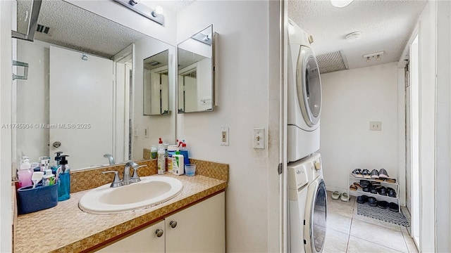 bathroom featuring tile patterned floors, stacked washer / dryer, a textured ceiling, and vanity