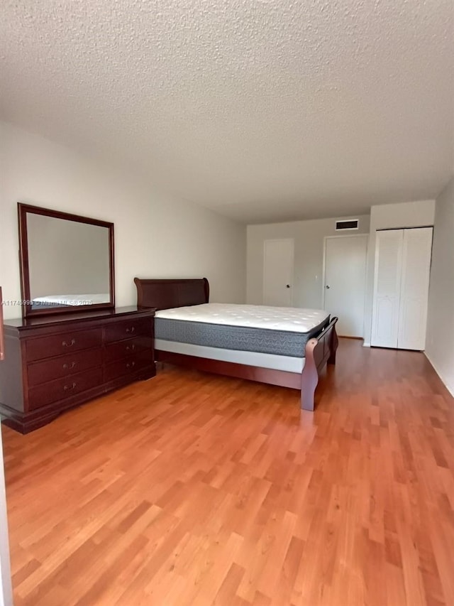 unfurnished bedroom with a textured ceiling and light wood-type flooring