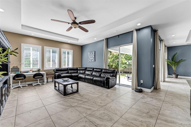 living room featuring light tile patterned floors, a tray ceiling, plenty of natural light, and ceiling fan