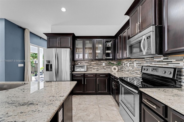 kitchen featuring sink, dark brown cabinets, stainless steel appliances, tasteful backsplash, and light stone countertops