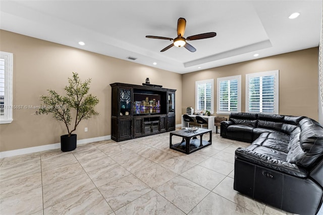 living room featuring ceiling fan and a tray ceiling