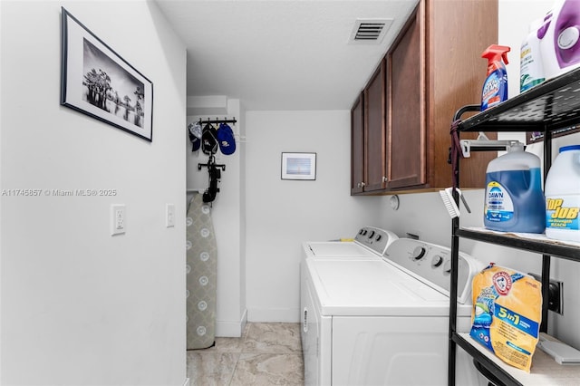 clothes washing area featuring washer and dryer and cabinets