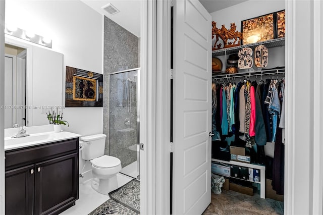 bathroom featuring vanity, a shower with door, and toilet