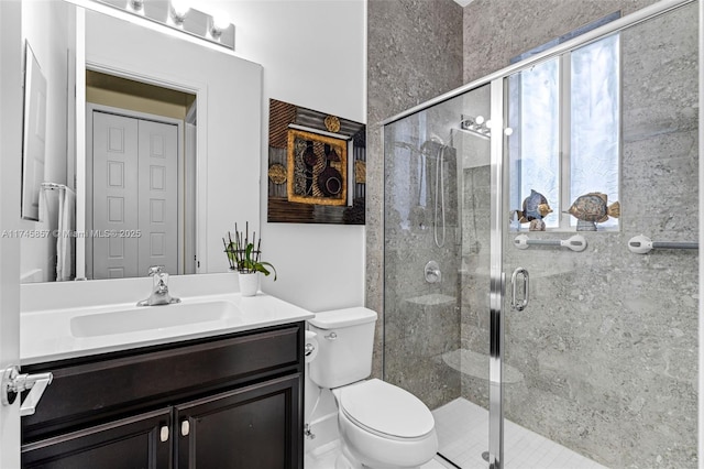 bathroom featuring a shower with door, vanity, and toilet