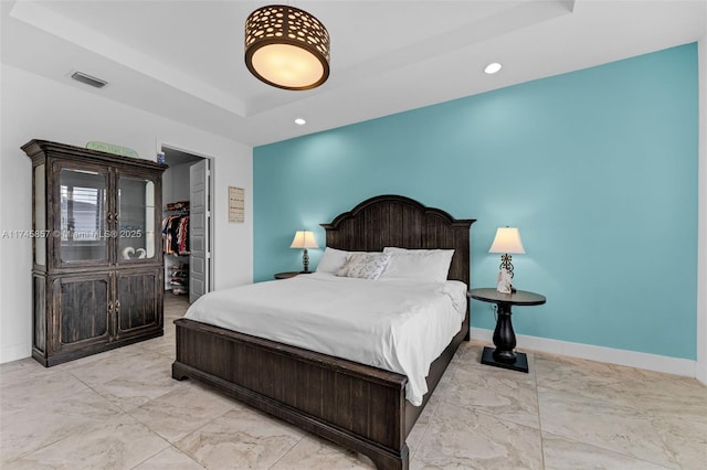 bedroom with a walk in closet, a tray ceiling, and a closet