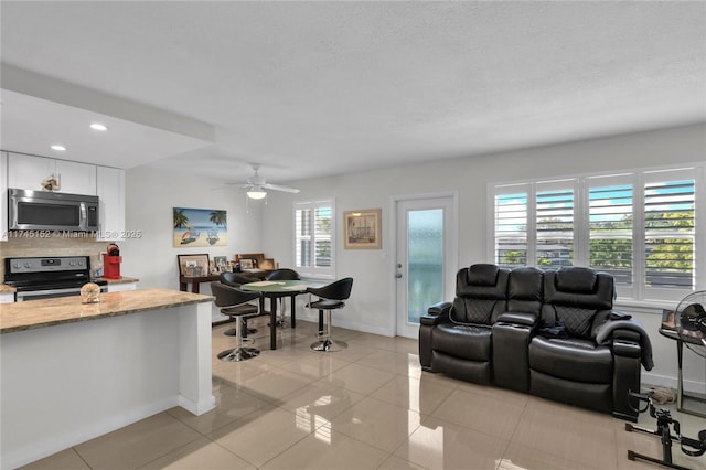 living room featuring recessed lighting, light tile patterned flooring, ceiling fan, a textured ceiling, and baseboards