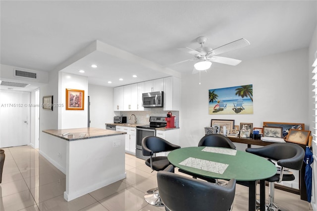 kitchen with light tile patterned flooring, appliances with stainless steel finishes, stone countertops, tasteful backsplash, and white cabinets