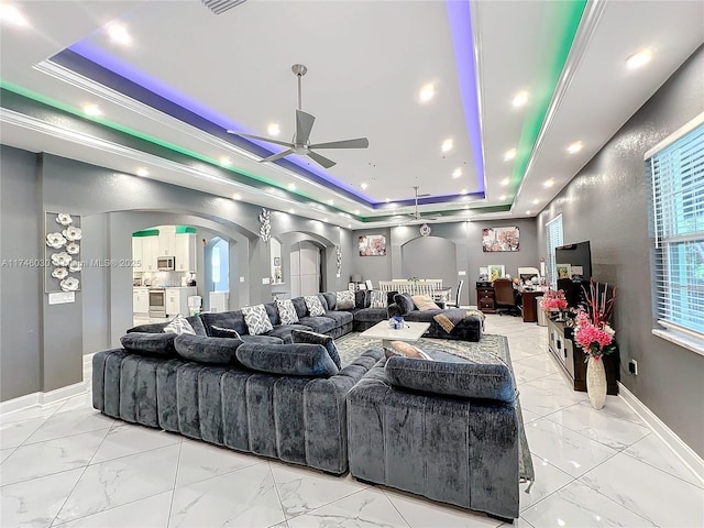 interior space featuring a tray ceiling, crown molding, arched walkways, and baseboards