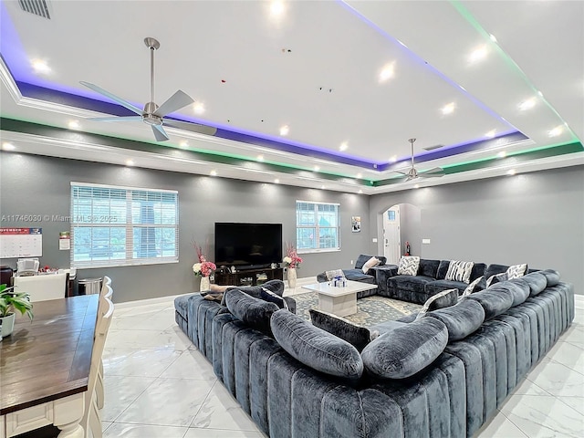 living room with arched walkways, a raised ceiling, ceiling fan, and marble finish floor