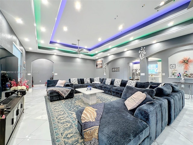 living area featuring arched walkways, baseboards, marble finish floor, ornamental molding, and a raised ceiling