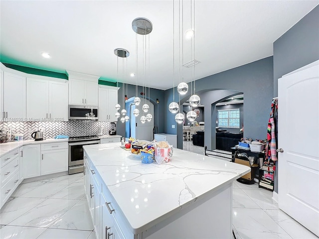 kitchen featuring white cabinetry, appliances with stainless steel finishes, pendant lighting, and a center island