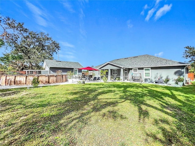 rear view of house with fence, a lawn, and a patio