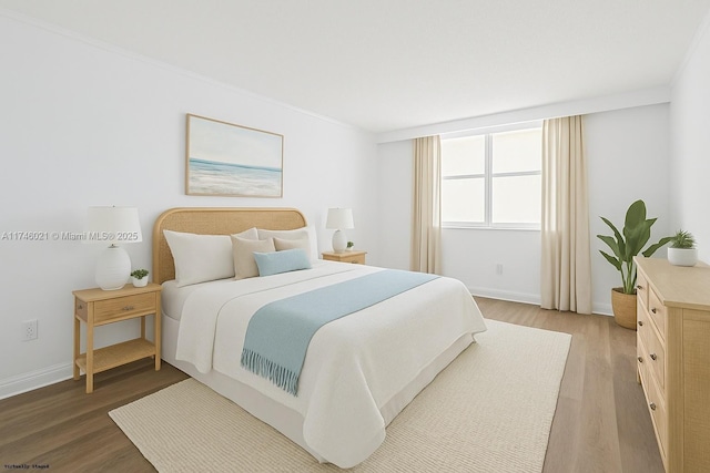 bedroom with light wood-style floors, baseboards, and ornamental molding