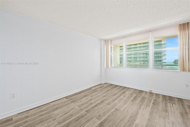 unfurnished room featuring a textured ceiling, ornamental molding, and wood finished floors